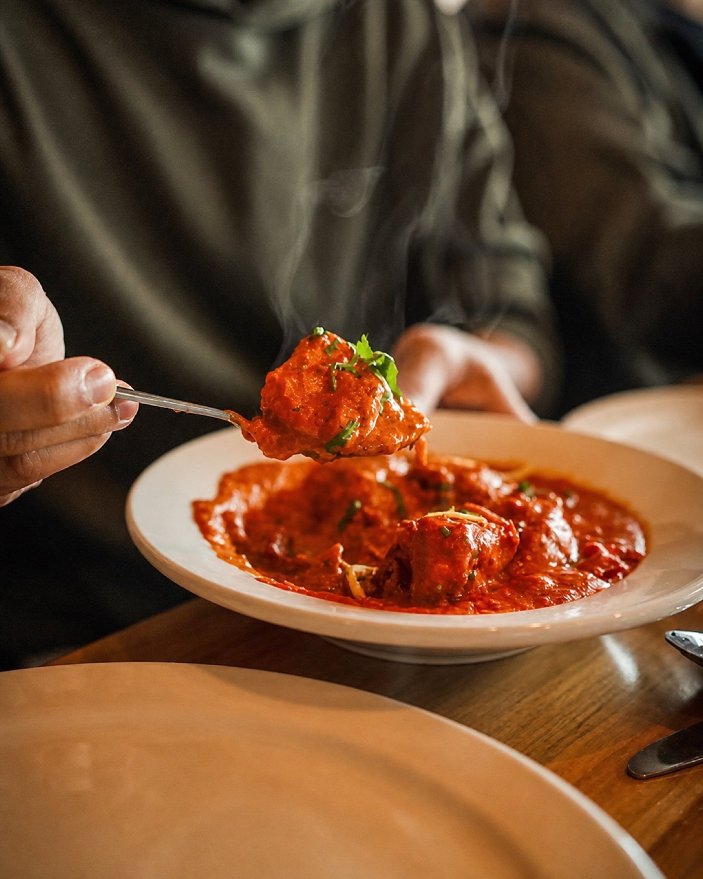 A guest lifting a piece of curry from a plated dish at Samway Grill